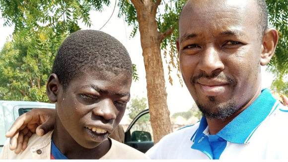 Boy with trichiasis and Sightsavers project officer before his surgery