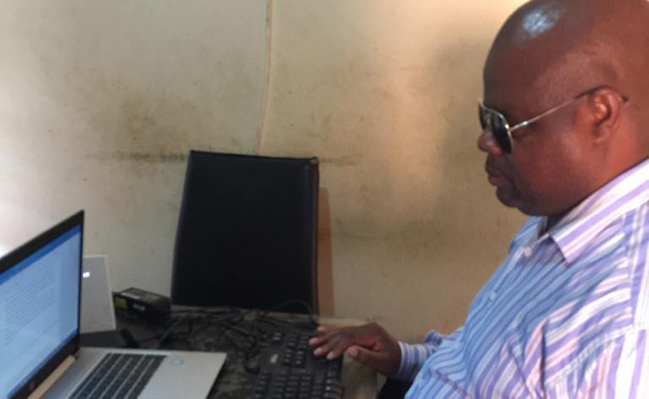 Thomas Mtonga sitting at his laptop.