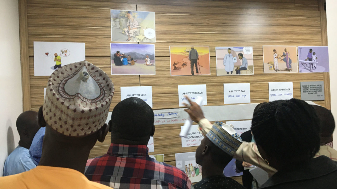 A group of people look at a wall where cartoons representing the research are shown.