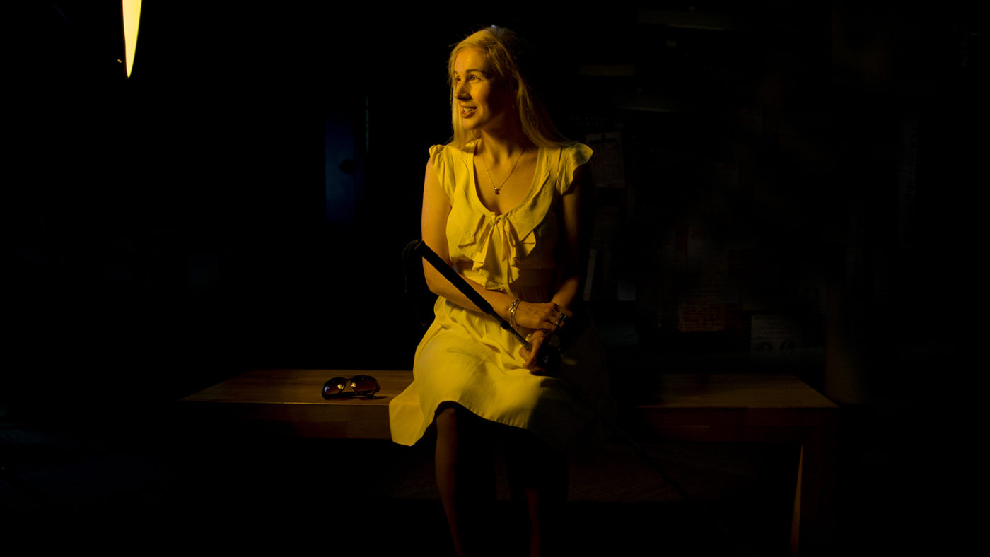 Sinead sits for a portrait wearing a yellow dress.