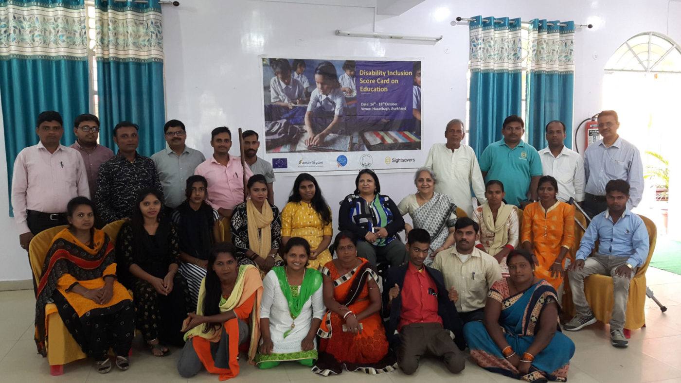 A large group of about 25 people with disabilities in an office setting posing for a photo.