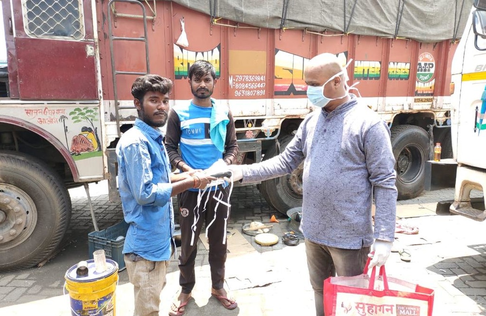 A man wearing a mask hands masks to two other men.