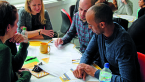 A group of Sightsavers employees around a desk working on a project.