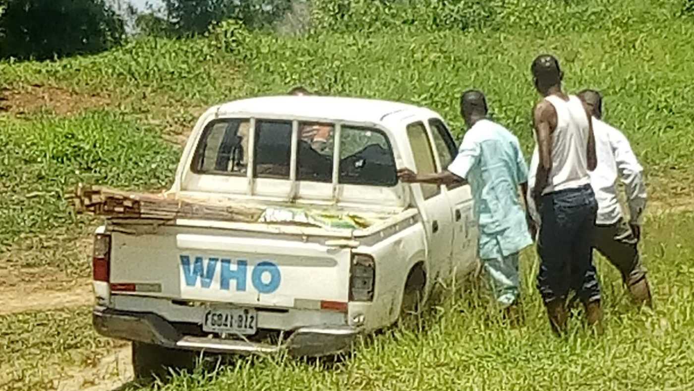 Three men push a truck out of the mud.