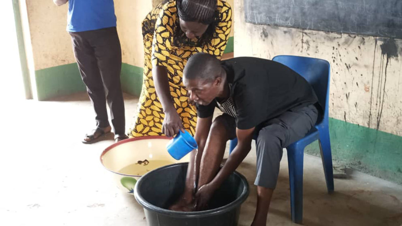 A woman helps a man wash his leg.
