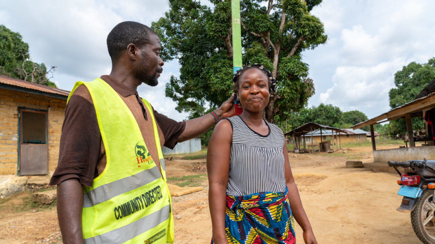 A man uses a dose pole to measure a woman's height.