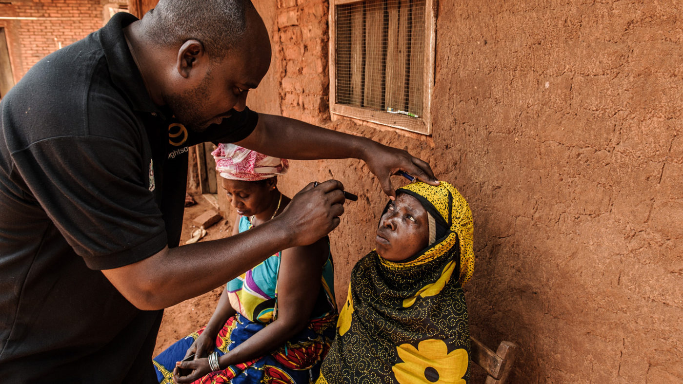 A doctor examining the sore eye of a woman with advanced trachoma.