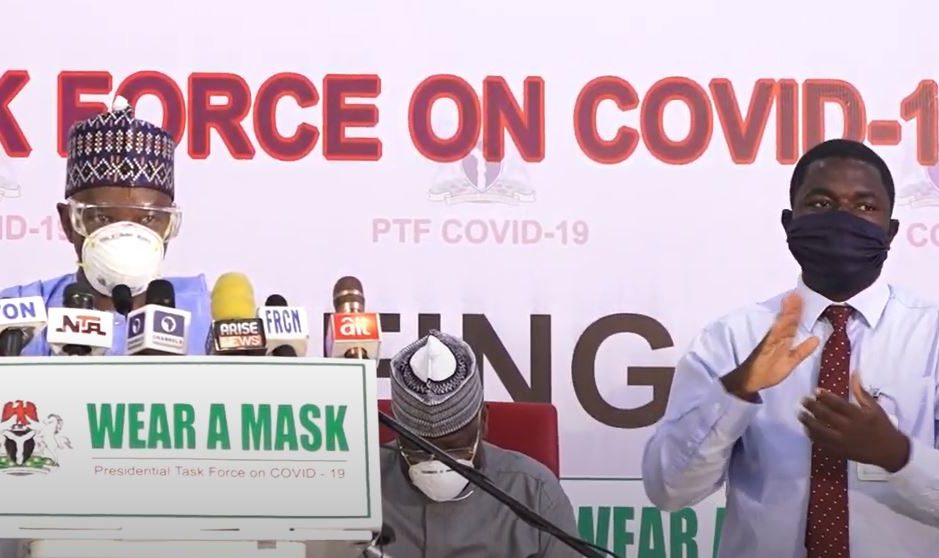 A sign language interpreter stands next to a speaker at the Task Force for COVID-19 presentation in Nigeria.