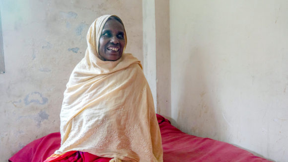 A woman sitting on a hospital bed smiling.
