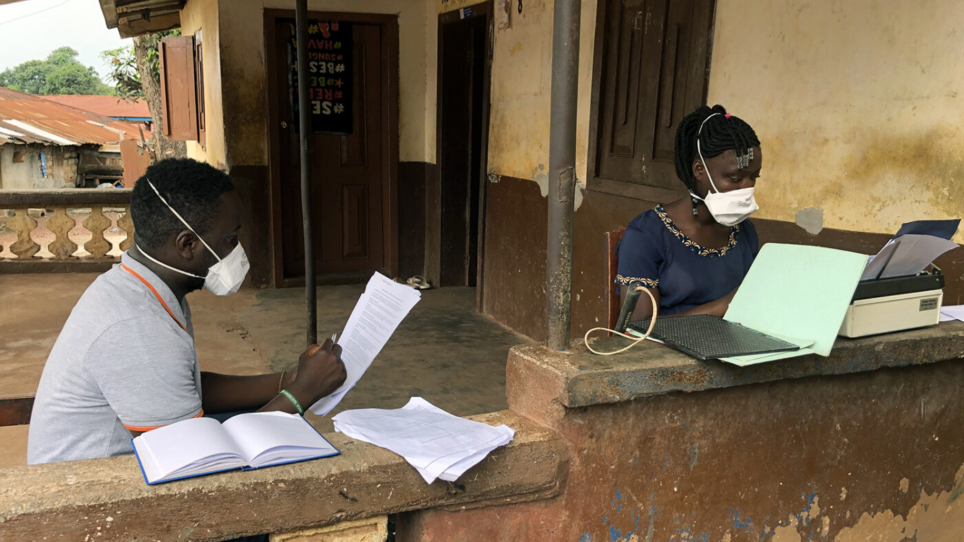 A man and girl sit outside with face masks on.