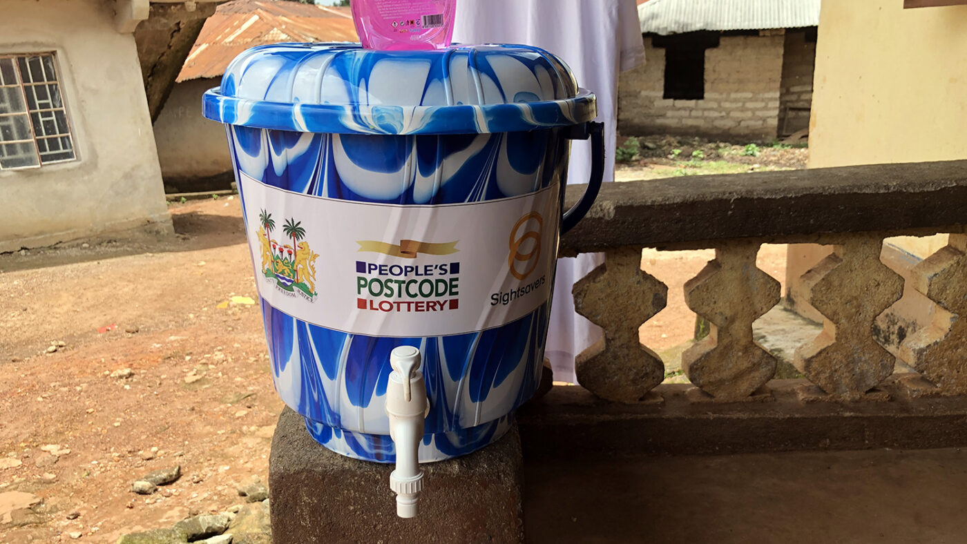 A water bucket with Sightsavers and People's Postcode Lottery logos on the front.