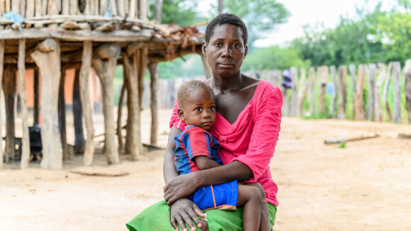 A mother sitting down, holding her child who is sat on her lap.
