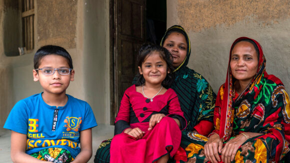 Two women sit with two childen outside.