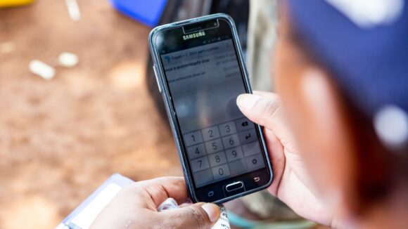 A person's hands are shown, entering data into a mobile phone