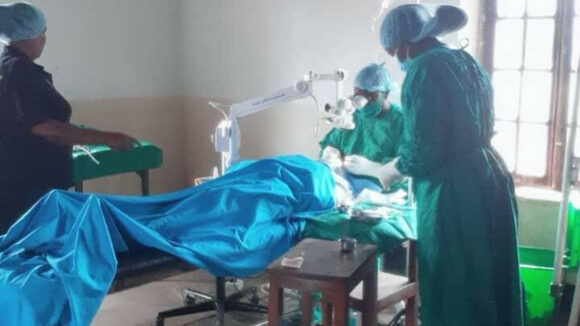 Two nurses and a surgeon are working on a patient.