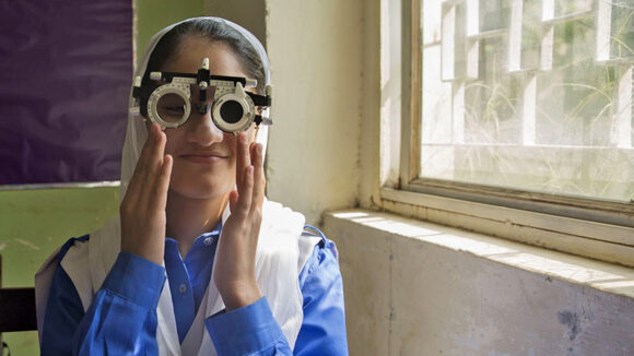 A girl smiles as she has her eyes tested.