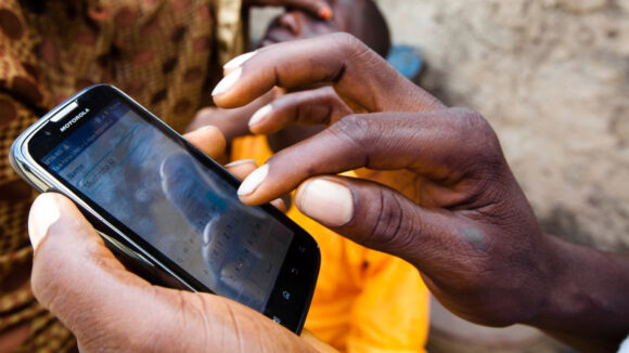 A close-up of a mobile phone being used by a health worker to record data.