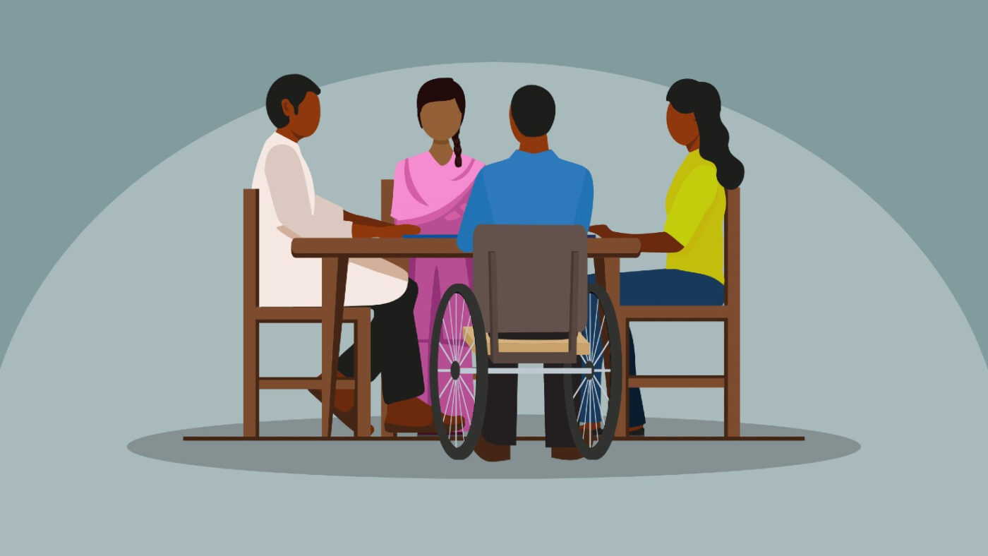 An illustration showing a group of people sitting at a table, talking together. One person in the group is a wheelchair user.