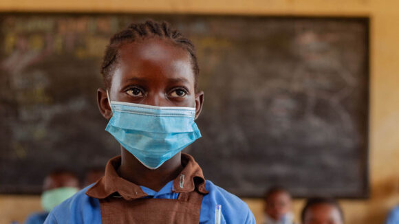 A girl wearing a face mask in a classroom.