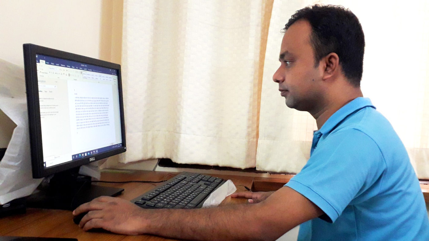 Subrata wearing a blue t-shirt and working on a computer.
