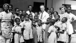 A historic black and white photo with Sightsavers founder Sir John Wilson and his wife Lady Jean surrounded by staff and children from Akropong school in Kenya.