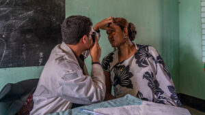 An eye health worker shines a torch into Bristy's eye during an eye exam.