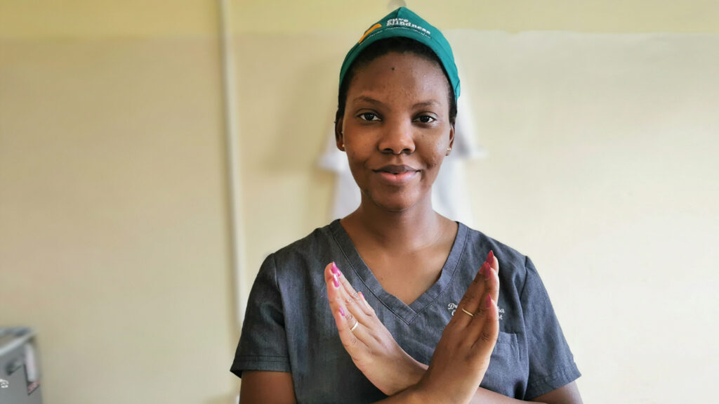 Dr Jalikatu wearing surgical scrubs, holding her hands crossed in front of her chest.
