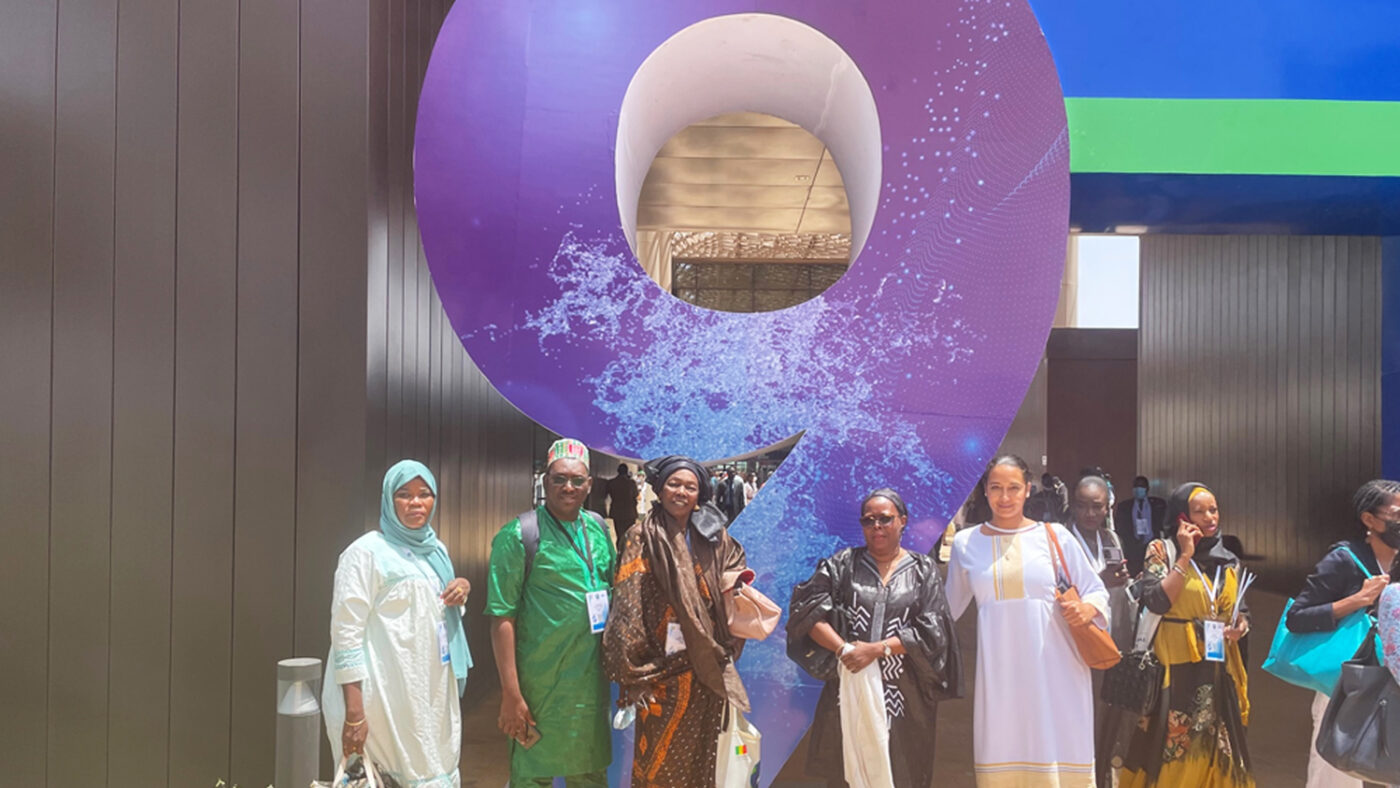 A group of five women stand outside in front of a large 'nine' - marking the ninth World Water Forum