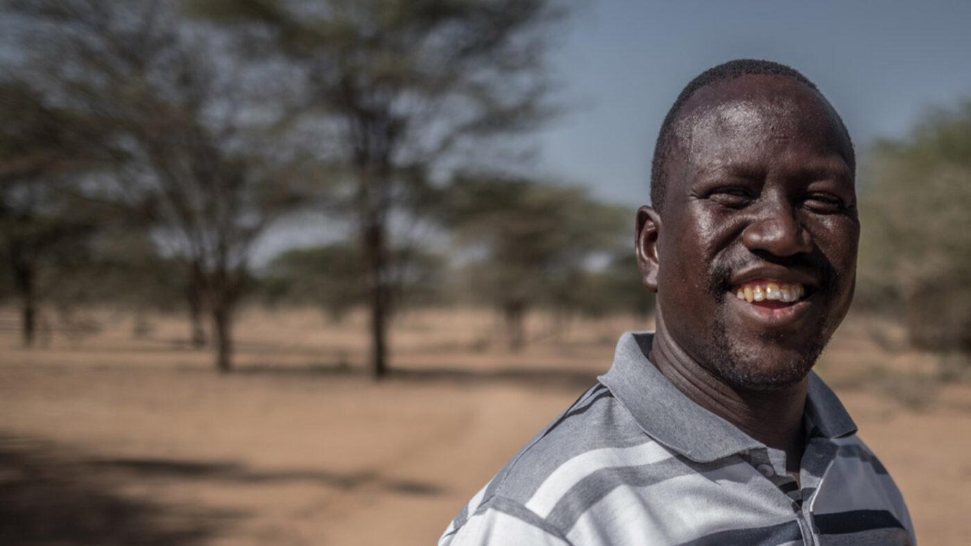 Samson stands outside and smiles at the camera.