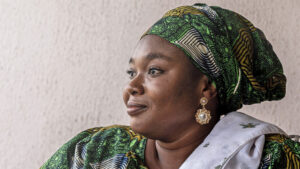 Salihu loosk away from the camera. She's wearing a beautiful green headscarf that matches her clothing.