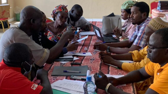 A group of people gather around a table during a VLR workshop.