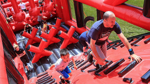 Competitors and kids running up a huge red inflatable staircase.