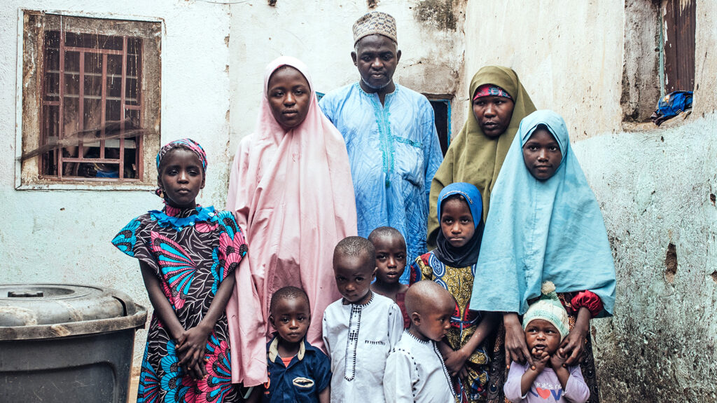 The family stand outside their home in Nigeria.
