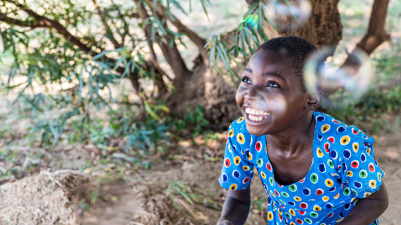 Mary from Malawi smiles as she chases bubbles near her home.