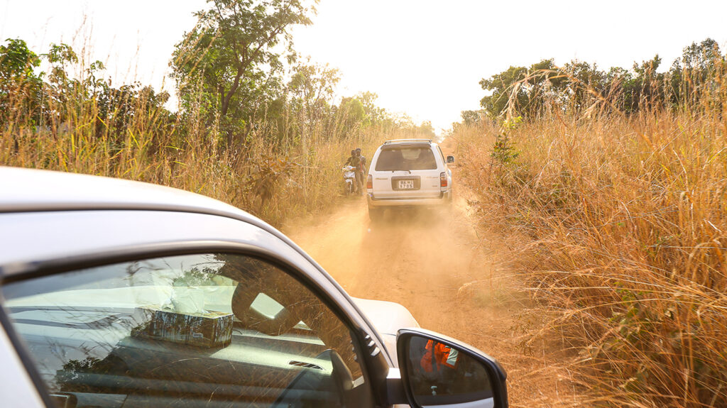 Trucks driving through a dusty rural track in Benin.