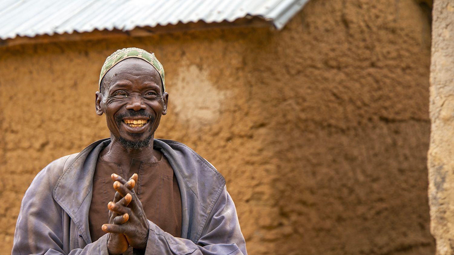 Adou smiles outside his home.