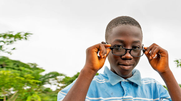 Arthur looks into the camera and holds his new glasses.