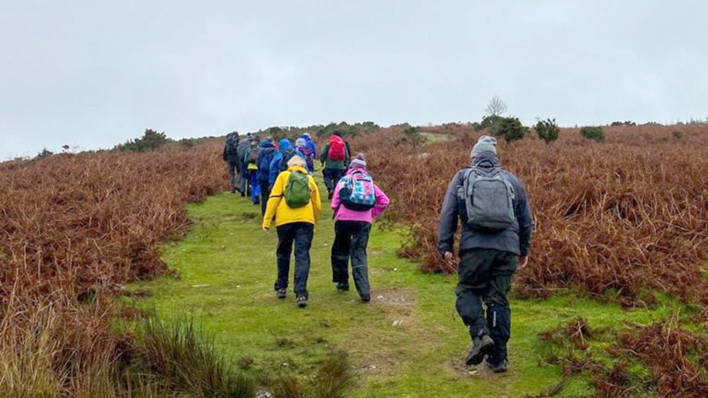 A group of people wearing outdoor clothes walk up a steep hill in the Wicklow Mountains.