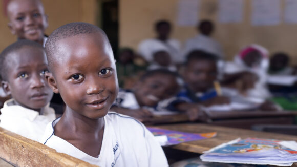 A young student in Nigeria smiles in the classroom.
