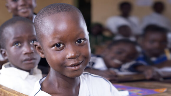 A young student in Nigeria smiles in the classroom.