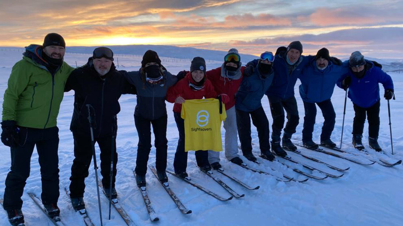 Participants on the First Light for Sight Arctic expedition poses for a group photo while wearing skis.