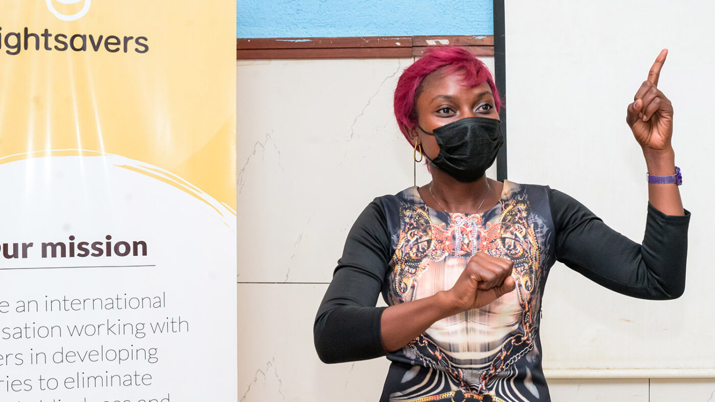 Leonie, who is wearing a medical face mask, gestures while doing a presentation.