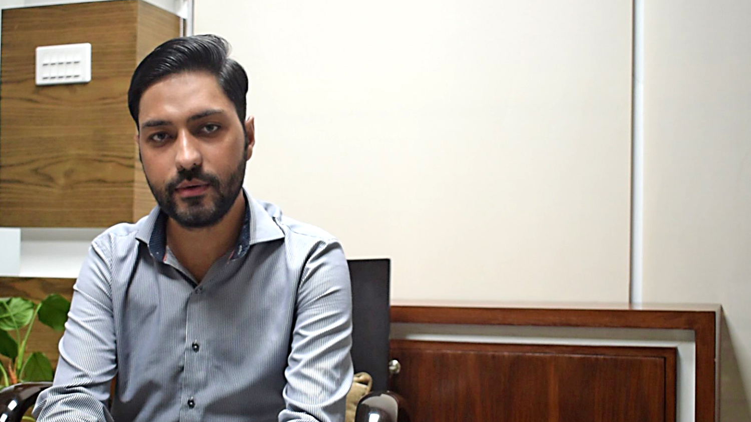 Ismail sitting in his office, wearing a smart shirt.