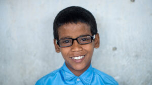 Shahid smiles for a portrait wearing his glasses.