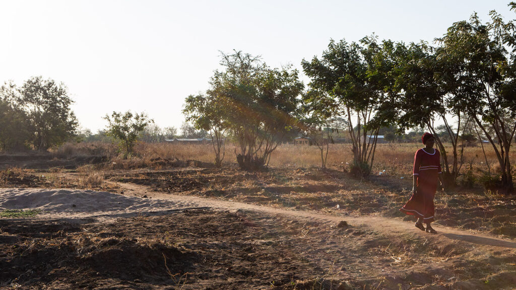 Community advocate Miriam walks through a field in Malawi.