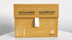 Sightsavers' bright yellow accessibility pack box standing on a desk.