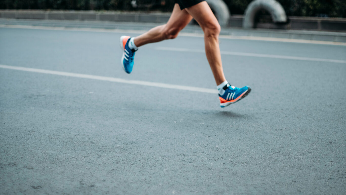 A single runner mid-stride running on a road