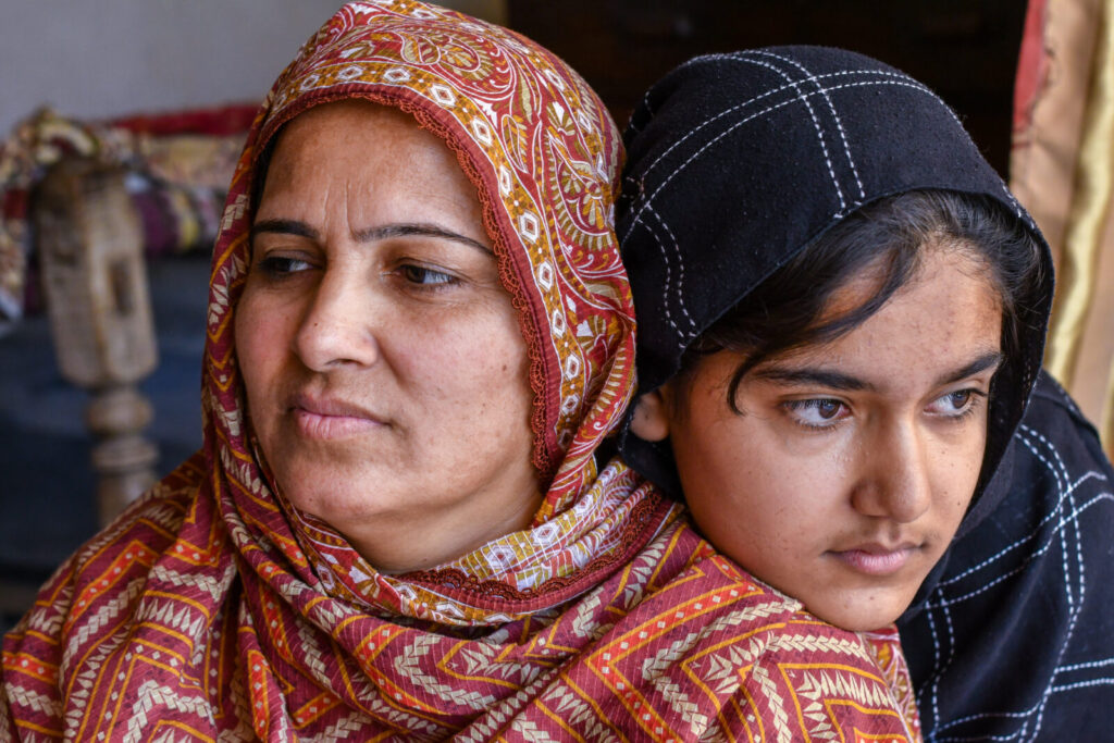 Zahra sits with her mother Zahida and rests her head on her mother's shoulder.