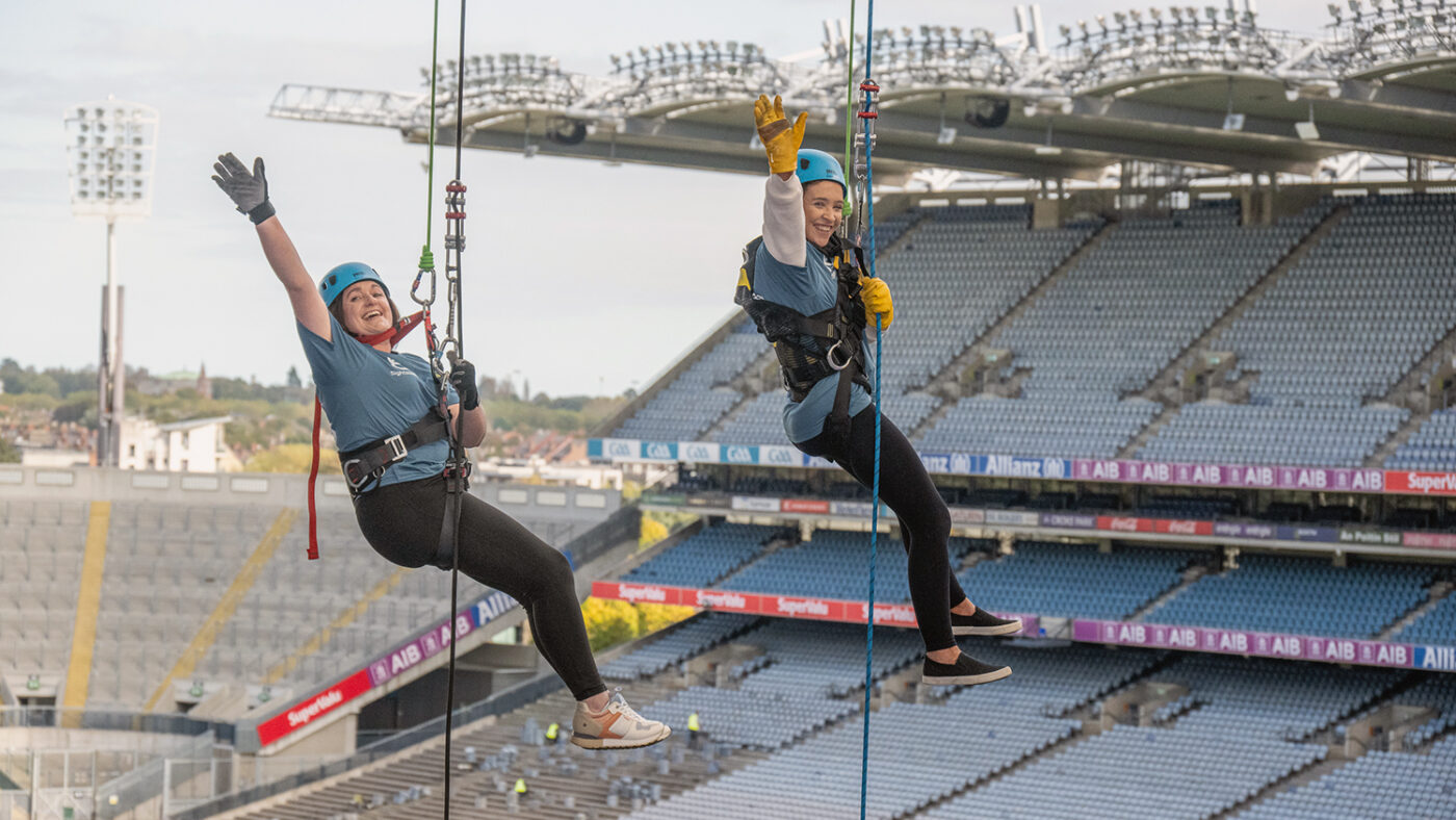 Two women wave while abseiling at the Croke Park stadium.