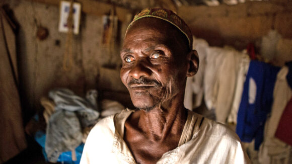 Mamodu from Ghana stands inside his home.